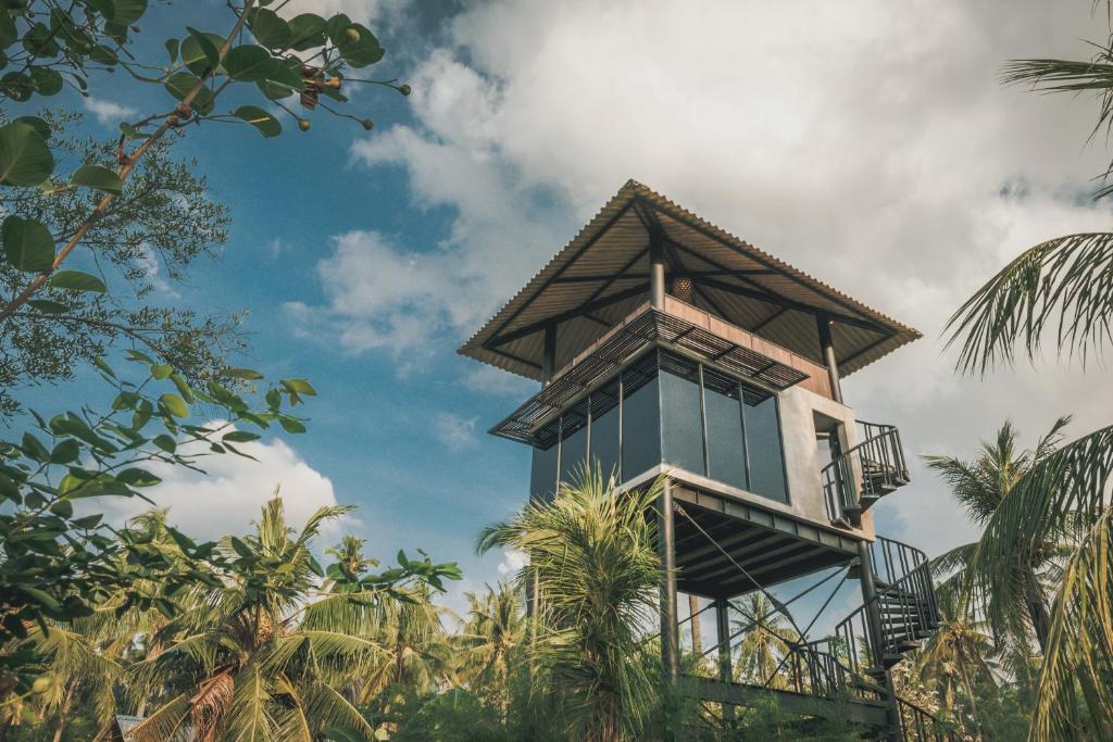 a tall building with a balcony and palm trees at Mangroove Bay Boutique Hostel in Banyuwedang