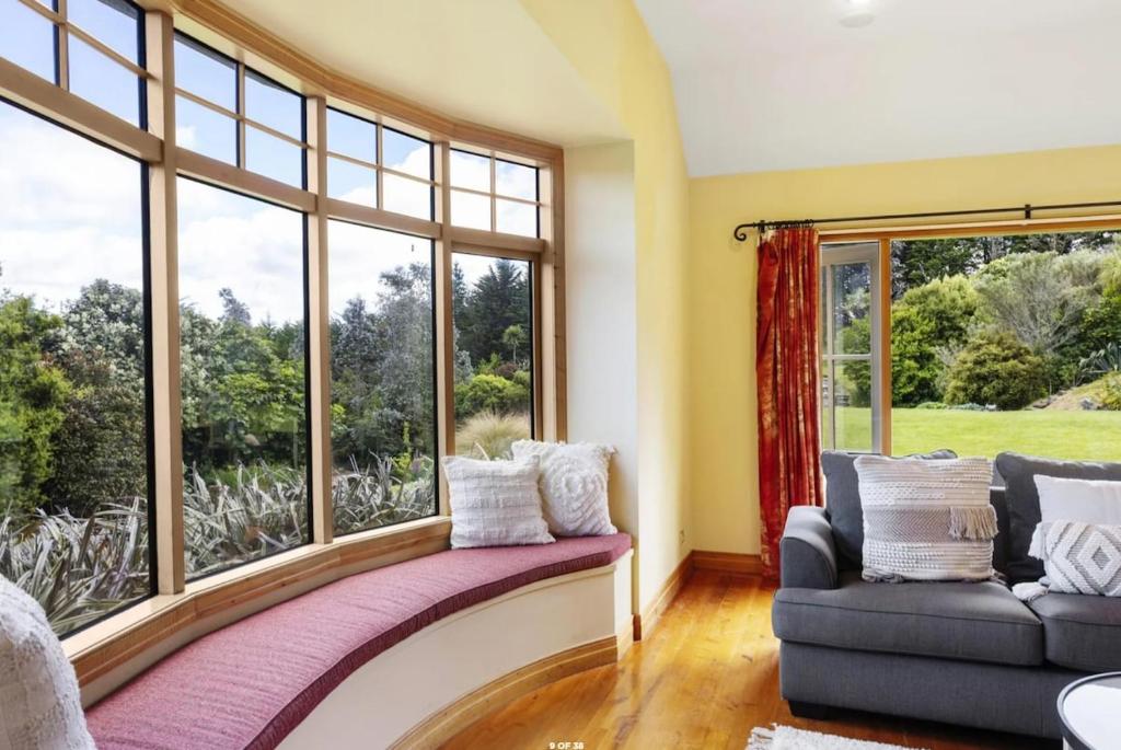 a living room with a couch and a large window at Peninsula Paradise in Dunedin