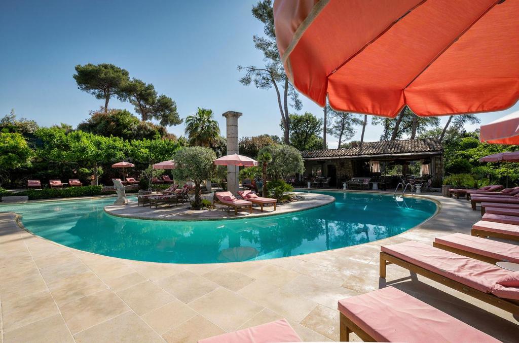 a swimming pool with a fountain and an umbrella at Hotel Les Messugues in Saint Paul de Vence