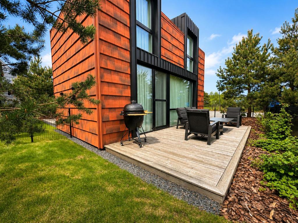 a house with a grill on a wooden deck at Sakalo kopa in Palanga