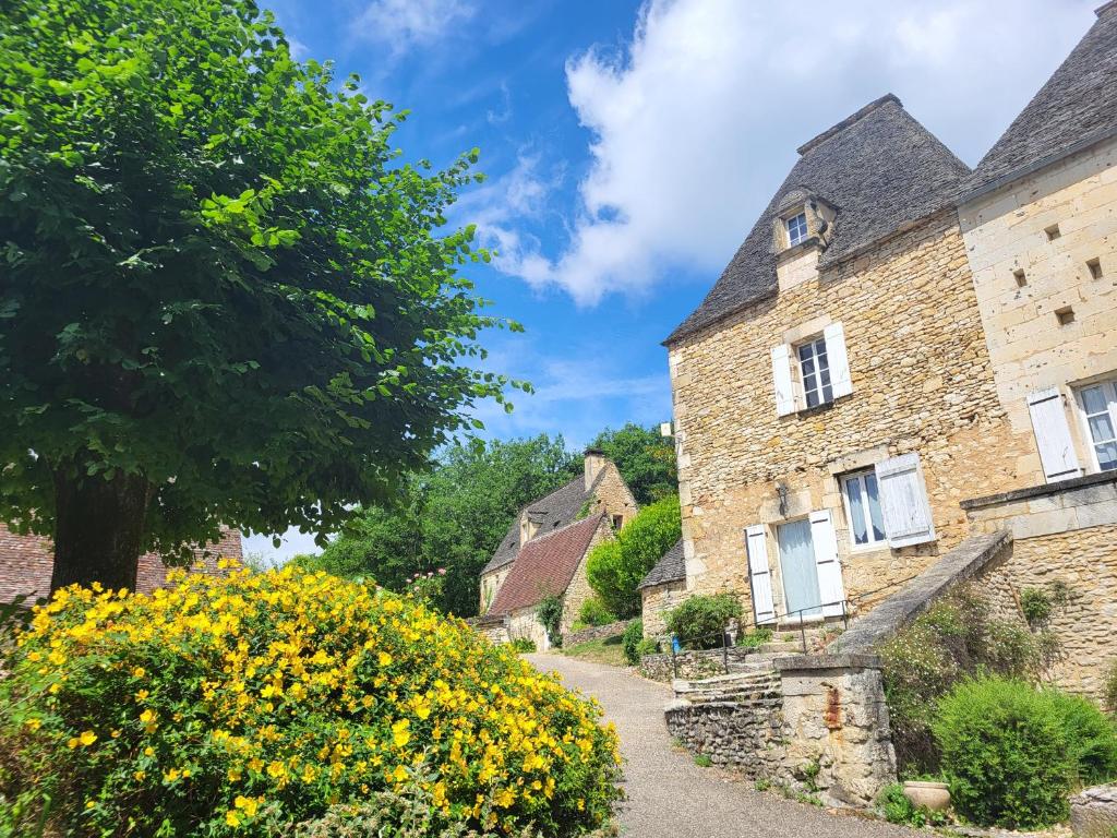 an old stone house in a village with yellow flowers at Domaine de Bagnegrole in Saint-Cyprien