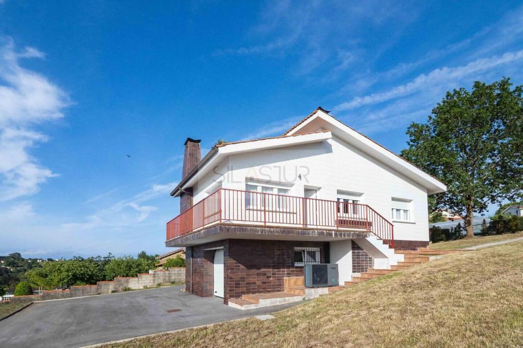 a white house with a balcony on a hill at Los Sauces By Silastur in Villaviciosa
