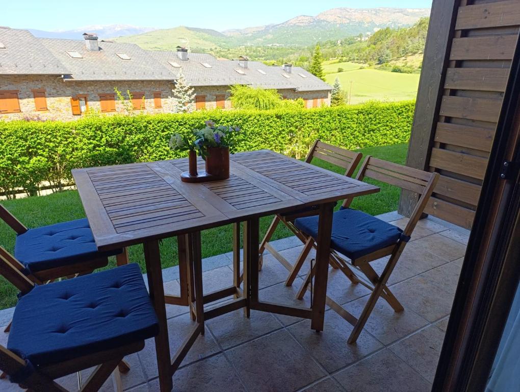 a wooden table and two chairs on a patio at Planta baja con jardín en Llívia in Llivia
