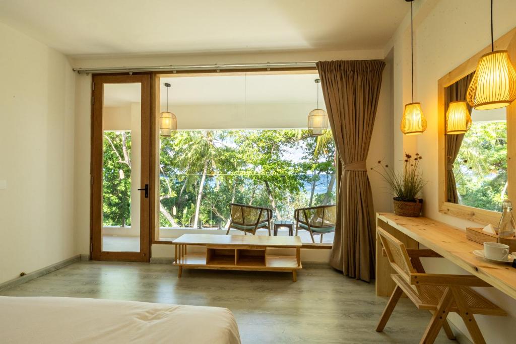 ein Schlafzimmer mit einem Bett, einem Schreibtisch und einem Tisch in der Unterkunft Odi Beachfront Kamadhoo in Kamadhoo