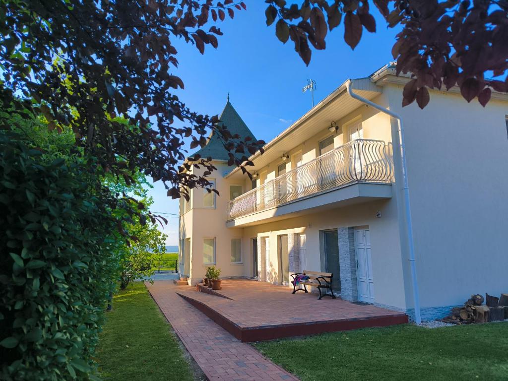 a large white building with a balcony and a patio at Angele Pihenőház in Balatonszárszó
