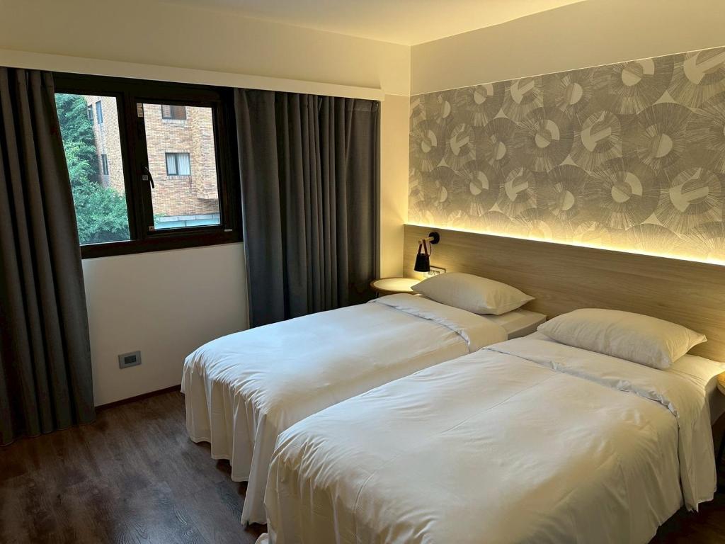 a hotel room with two beds and a window at Delight Hotel in Taipei