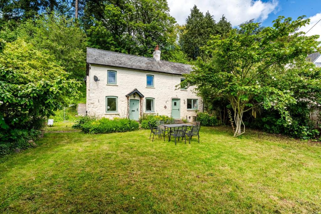 an old white house with a table in the yard at Charming 3-Bed Cottage by the River Usk in Abergavenny