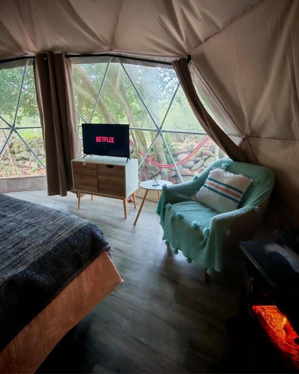 a bedroom with a bed and a tv in a tent at Glamp Refugio Silvestre 7 Tazas in Molina