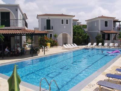 een groot zwembad met stoelen en een huis bij Portego in Laganas