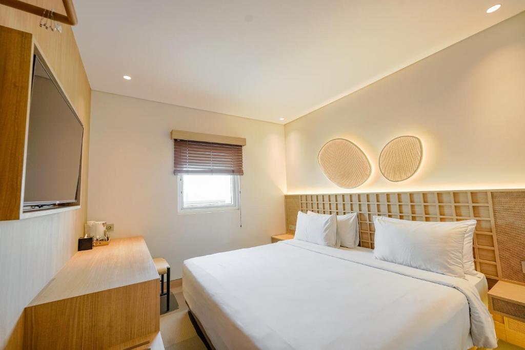 a bedroom with a large white bed and two mirrors at Kotta Kyu Hotel Semarang in Semarang