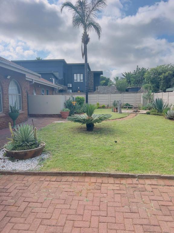 a yard with palm trees and a building at Mangena Legacy Guesthouse in Polokwane