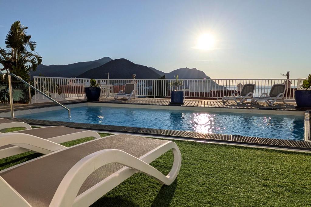 a swimming pool with lounge chairs in a yard at Apartamentos Julio Visconti in San José
