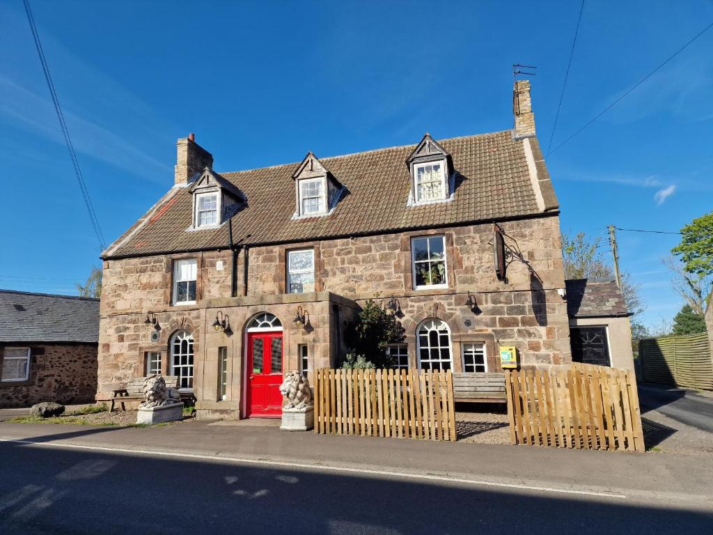 an old stone house with a red door at Red Lion Inn in Milfield