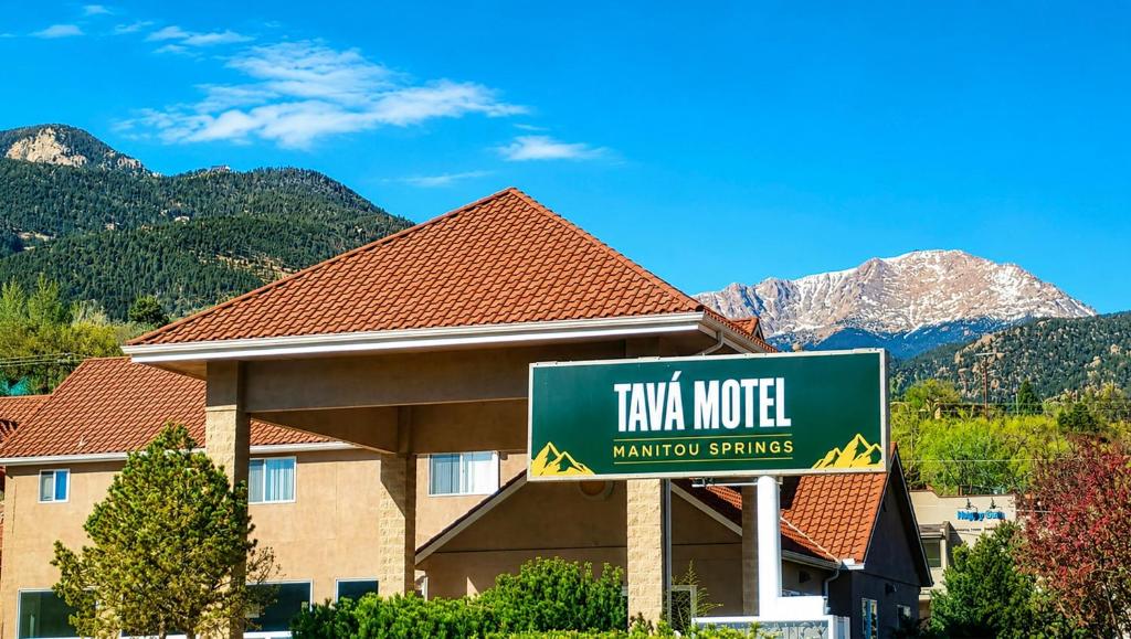 a sign for a hotel with mountains in the background at Tava Motel Manitou Springs in Manitou Springs