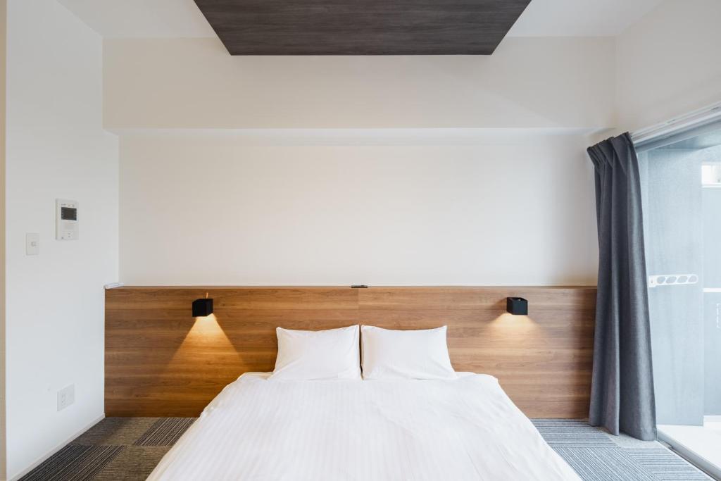 a bedroom with a white bed with a wooden headboard at HIT Tenjin in Fukuoka