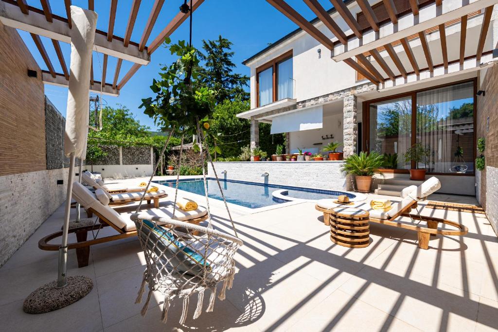a patio with chairs and a swimming pool at Villa D Apartments in Podlastva