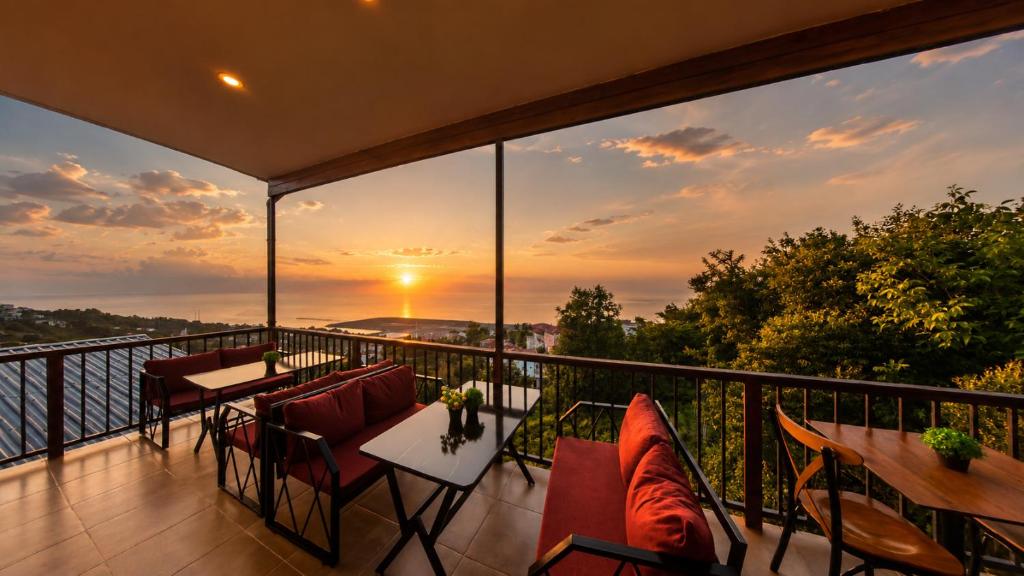 ein Balkon mit Tischen und Stühlen und ein Sonnenuntergang in der Unterkunft Bungaport Luxury Bungalows&Suits in Rize
