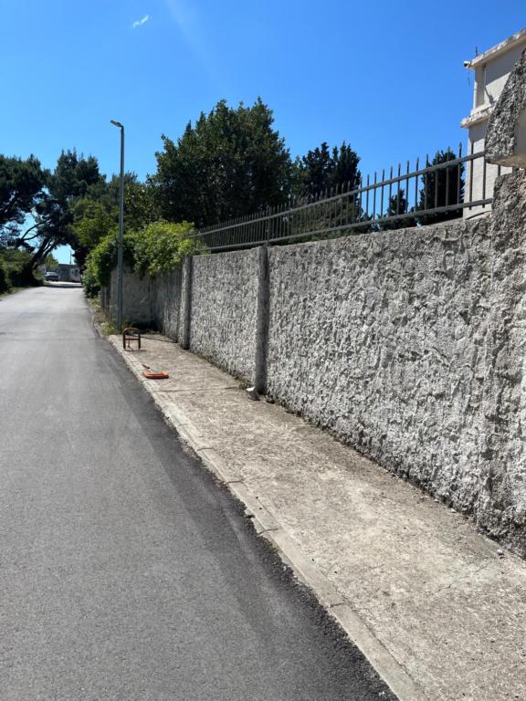 a stone wall next to a road next to a street at Obala Ineks in Sutomore