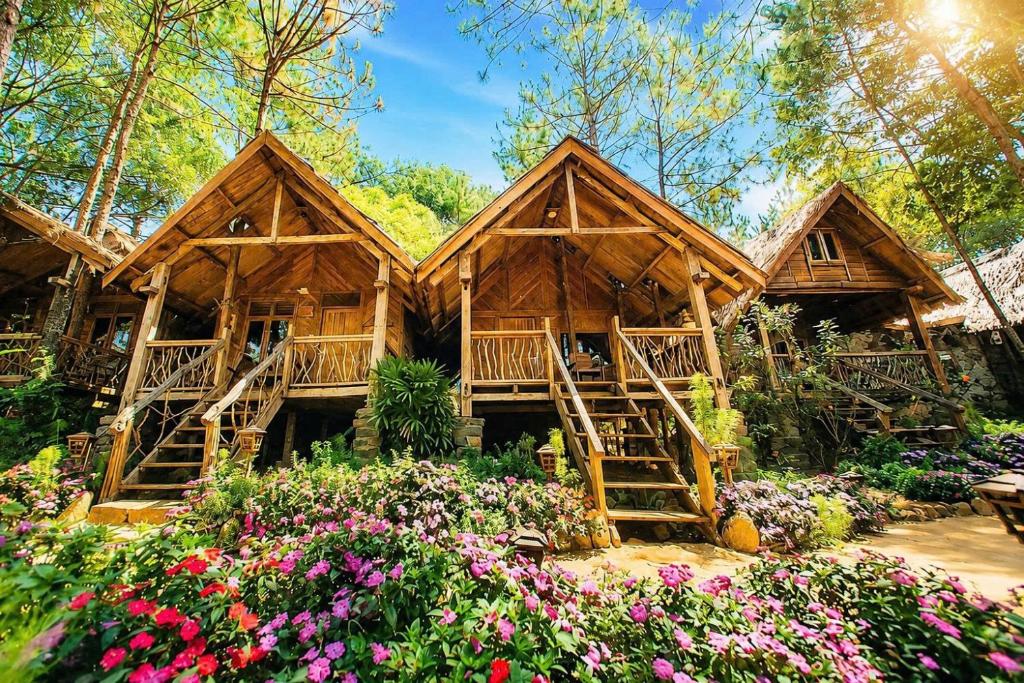 a log cabin in the woods with flowers at Sóc House Măng Đen in Kon Plong