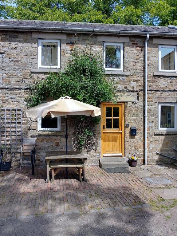 a table and an umbrella in front of a building at Mews Cottage in Middleton in Teesdale