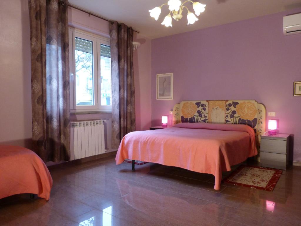 a bedroom with a bed with pink walls and a window at Elisir b&b in Pisa