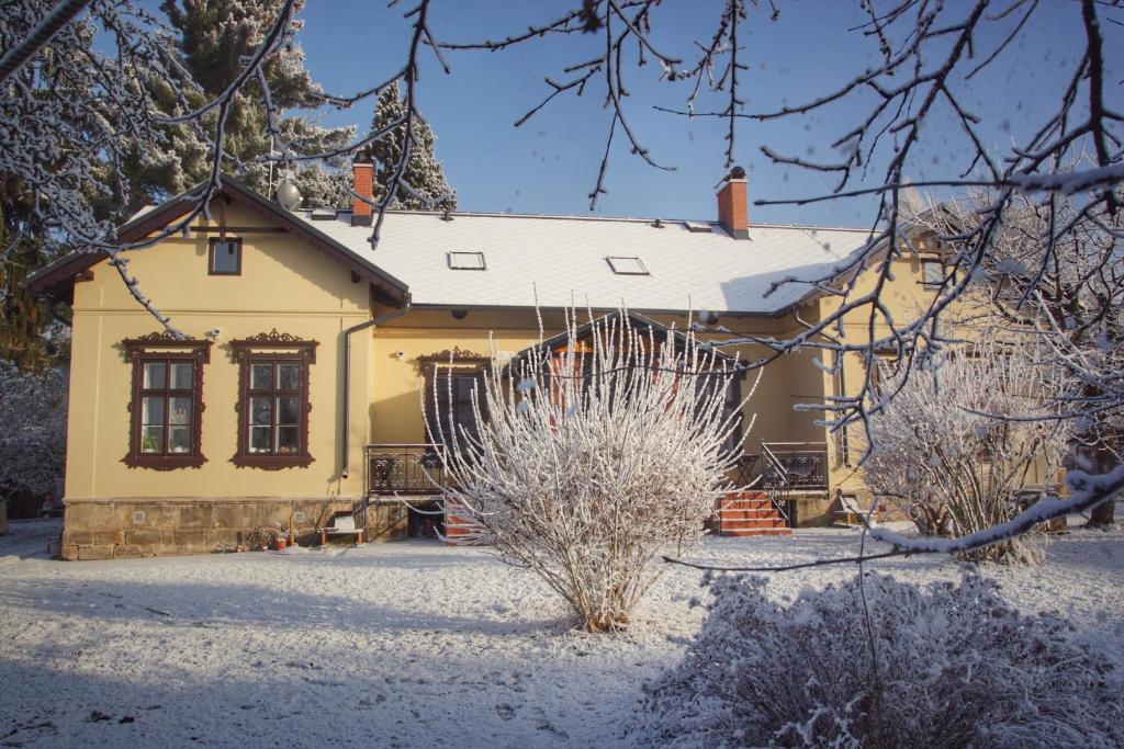 una casa amarilla con nieve en el suelo en Apartments Šimákova Vila, en Turnov