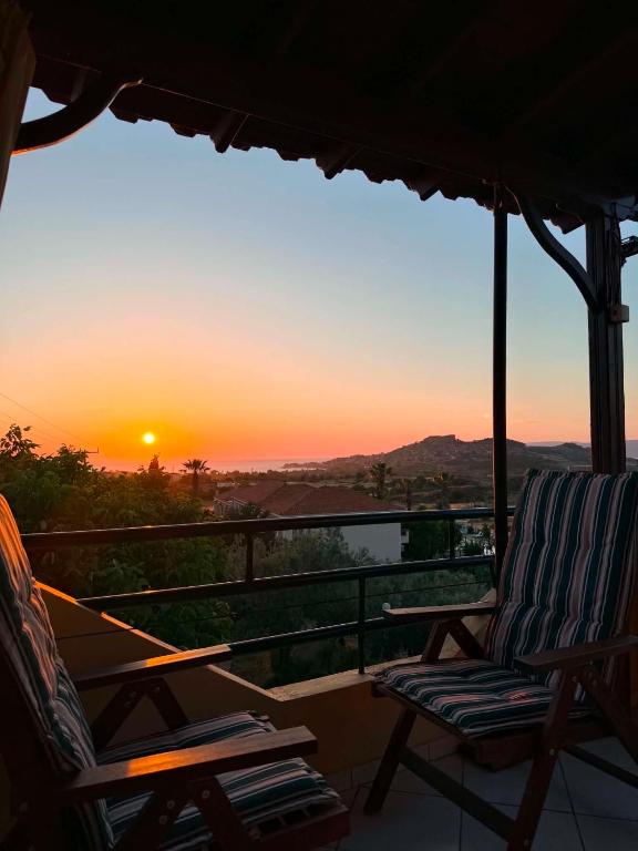 a couple of chairs sitting on a balcony with a sunset at Molyvos Sunset Horizon in Mythimna