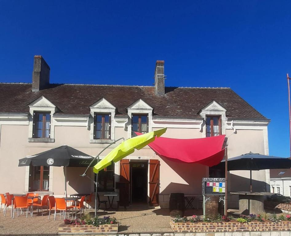 a building with umbrellas and chairs in front of it at Le Relais d'Heugnes in Heugnes