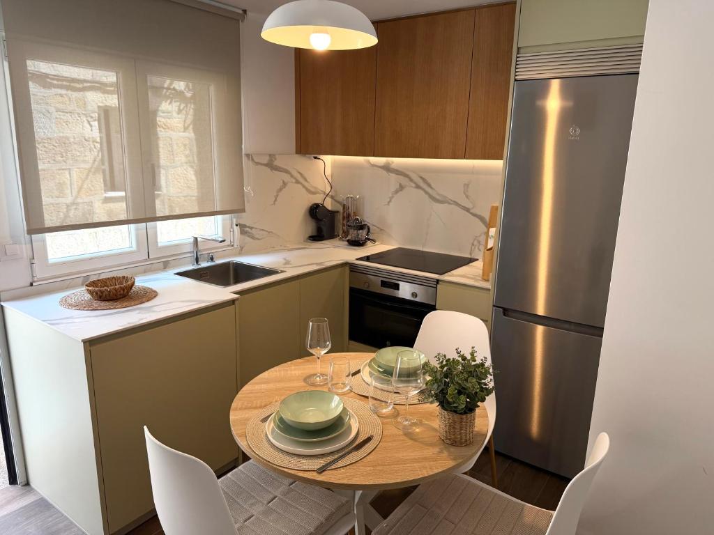 a kitchen with a table with chairs and a refrigerator at Casa Caracol in Cambados