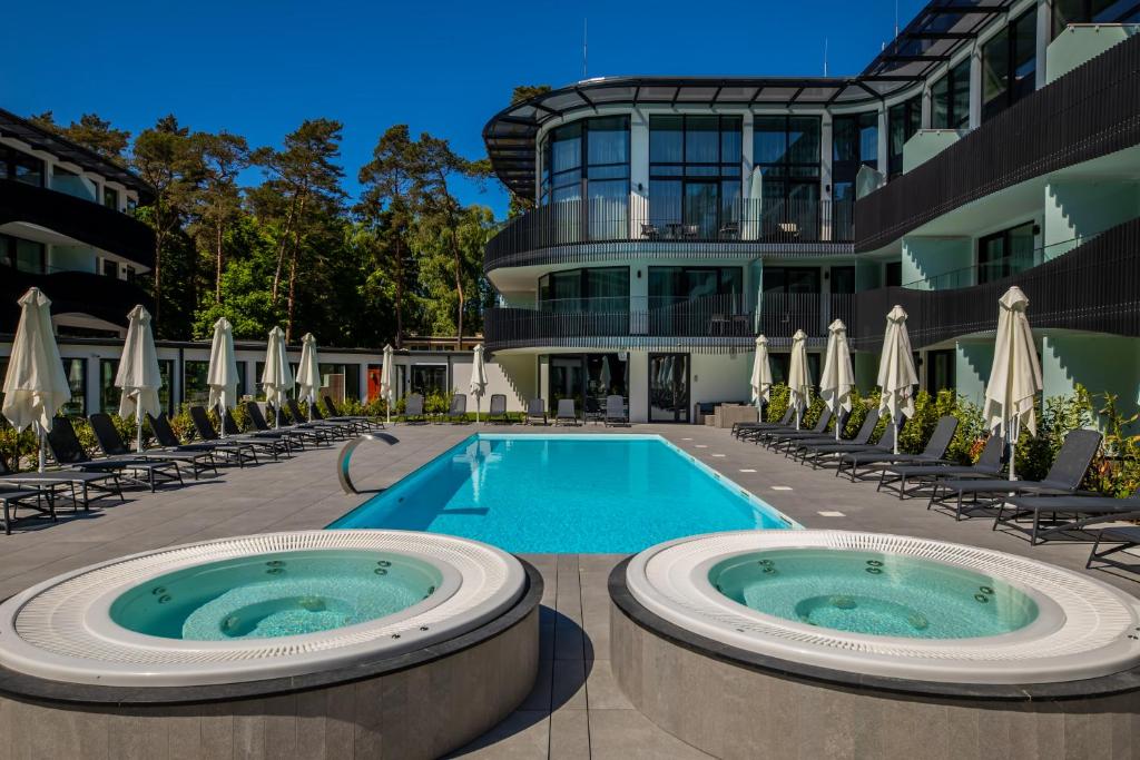 a pool at a hotel with chairs and umbrellas at Apartament Bursztynowa Komnata 117 Stegna nad morzem in Stegna