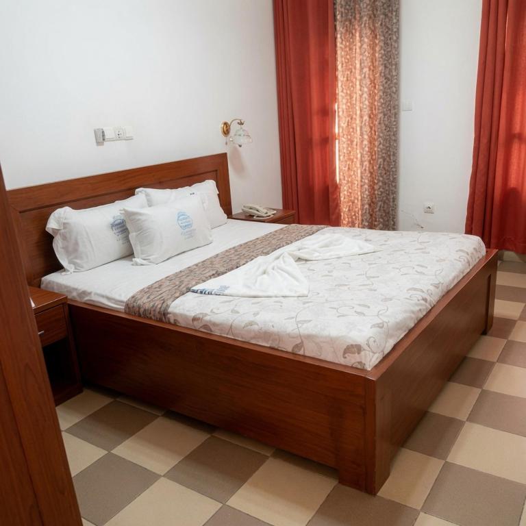 a bedroom with a wooden bed with white sheets at Arenah hotel in Yaoundé