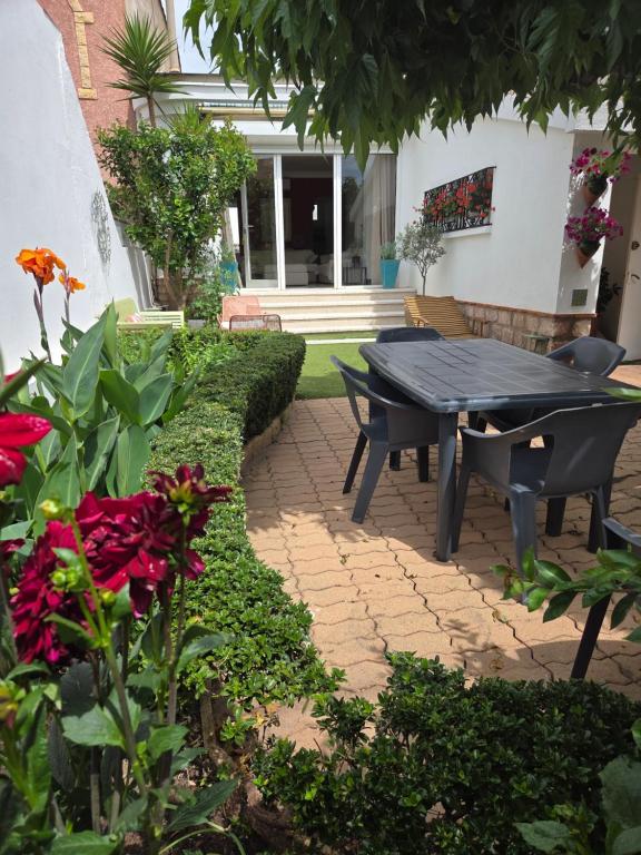 a patio with a table and red flowers at Maison Valras Plage très bon emplacement in Valras-Plage