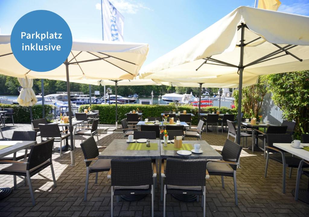 ein Restaurant mit Tischen, Stühlen und Sonnenschirmen in der Unterkunft Hotel Spree-idyll in Berlin