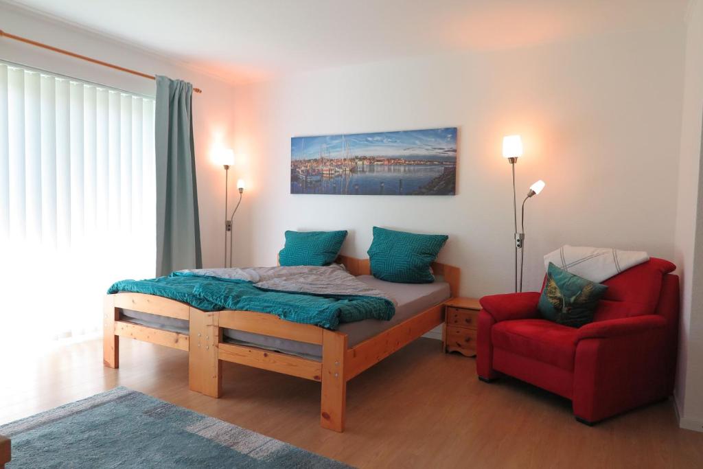 a bedroom with a bed and a red chair at Apartment "An der Süderschmiede" in Sieverstedt