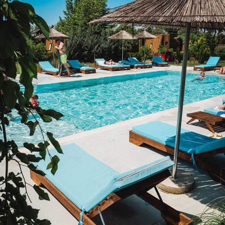 a swimming pool with lounge chairs and umbrellas in a resort at Mesopotam Agrotourism Resort in Sarandë
