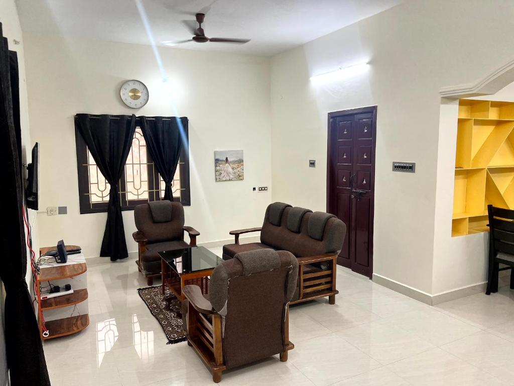 a living room with two chairs and a table at SK Aarshan's Homestay in Tiruchirappalli