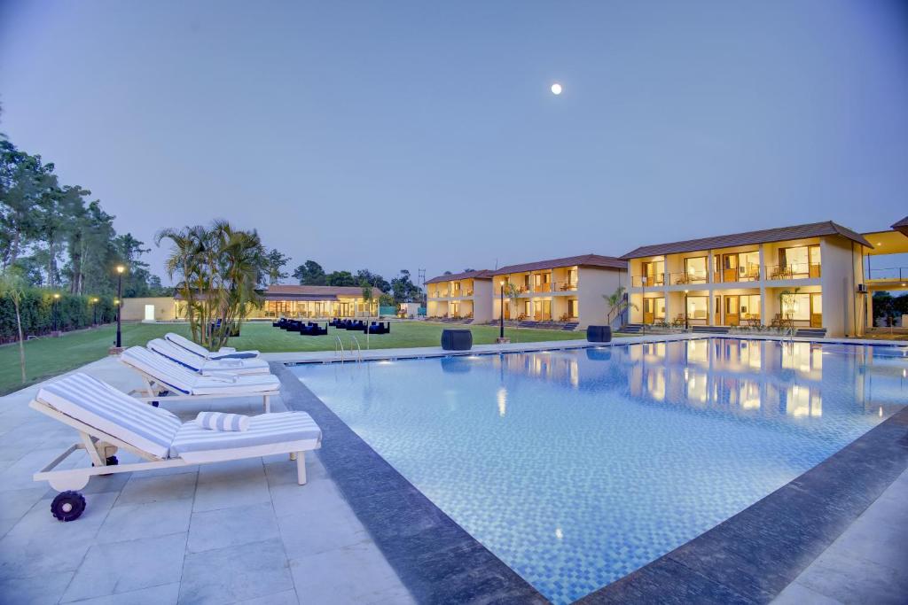 a swimming pool with two lounge chairs in front of a hotel at Cygnett Collection in Jim Corbett