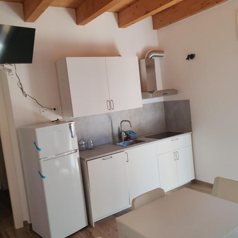 a kitchen with white cabinets and a refrigerator at New semi-detached two-room apartment in Monserrato