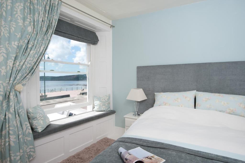 a bedroom with a bed and a window with a view of the beach at Sophia's in Penzance