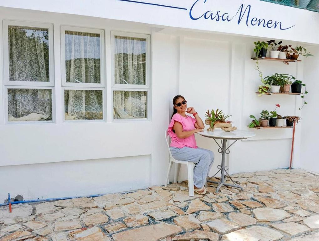a woman sitting at a table in front of a white building at Casa Nenen in Romblon