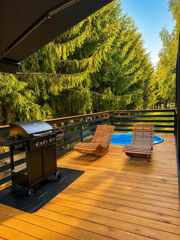 a grill on a deck with two chairs and a pool at Domki Na Talerzu in Skorochow