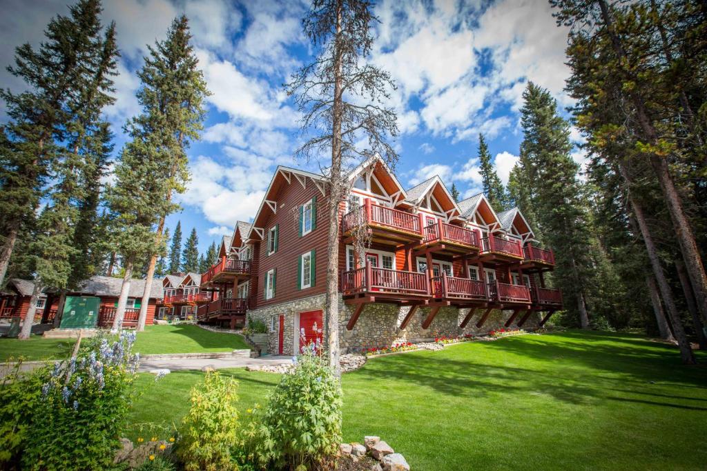 a large house with a deck on a green yard at Paradise Lodge and Bungalows in Lake Louise