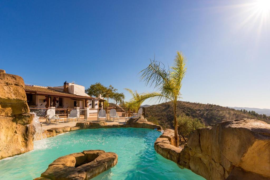 a swimming pool in a resort with a palm tree at Casa Miramar in Almogía