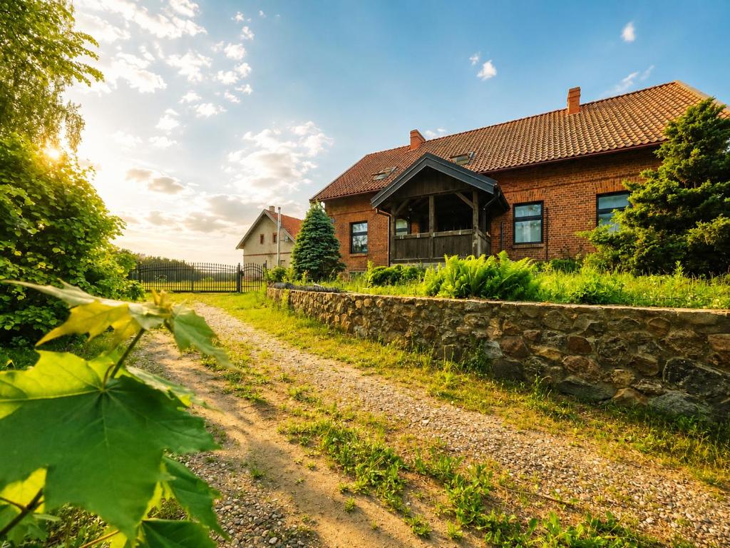 a brick house with a stone wall next to a dirt road at Siedlisko Drwęck in Drwęck