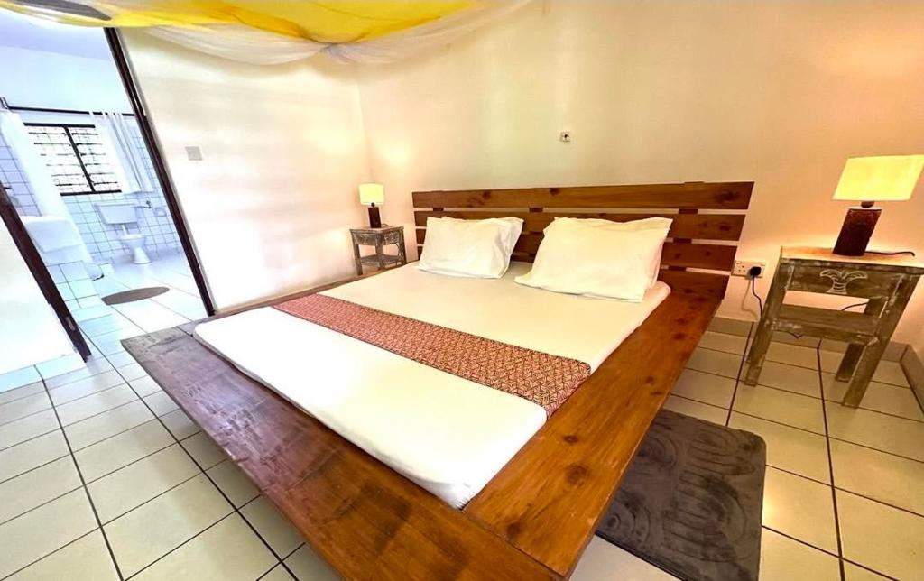 a bedroom with a wooden bed in a room at Beach House - private room in Diani Beach