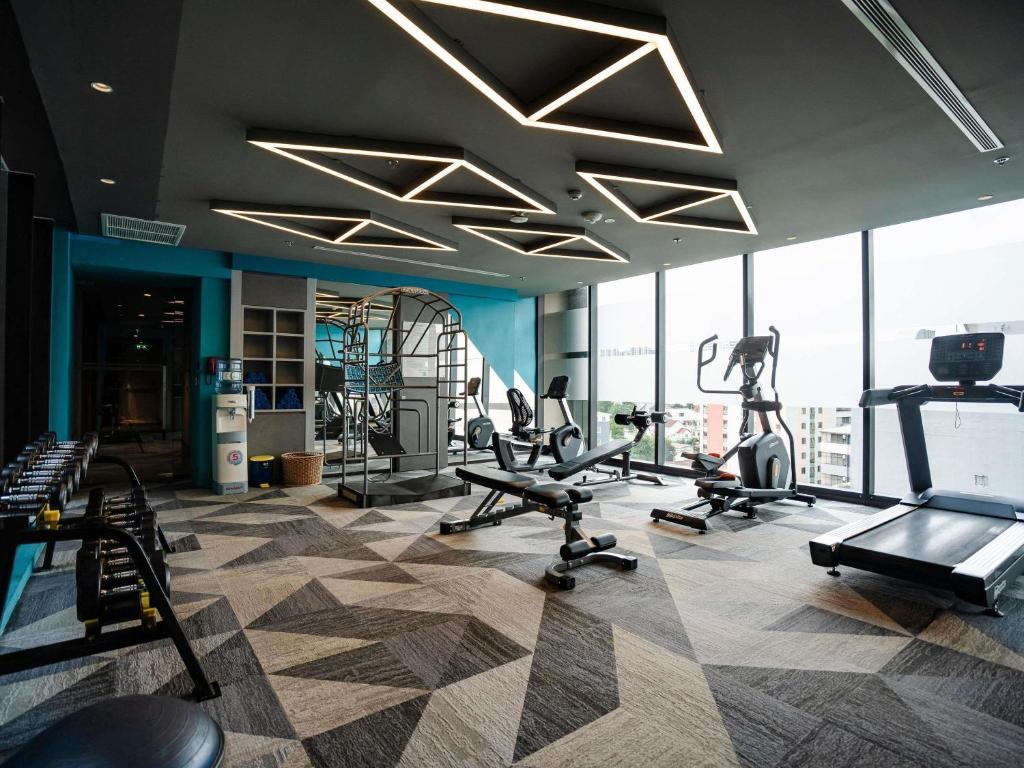 A spacious-looking gym with treadmills, ellipticals, dumbbells, and a bench.