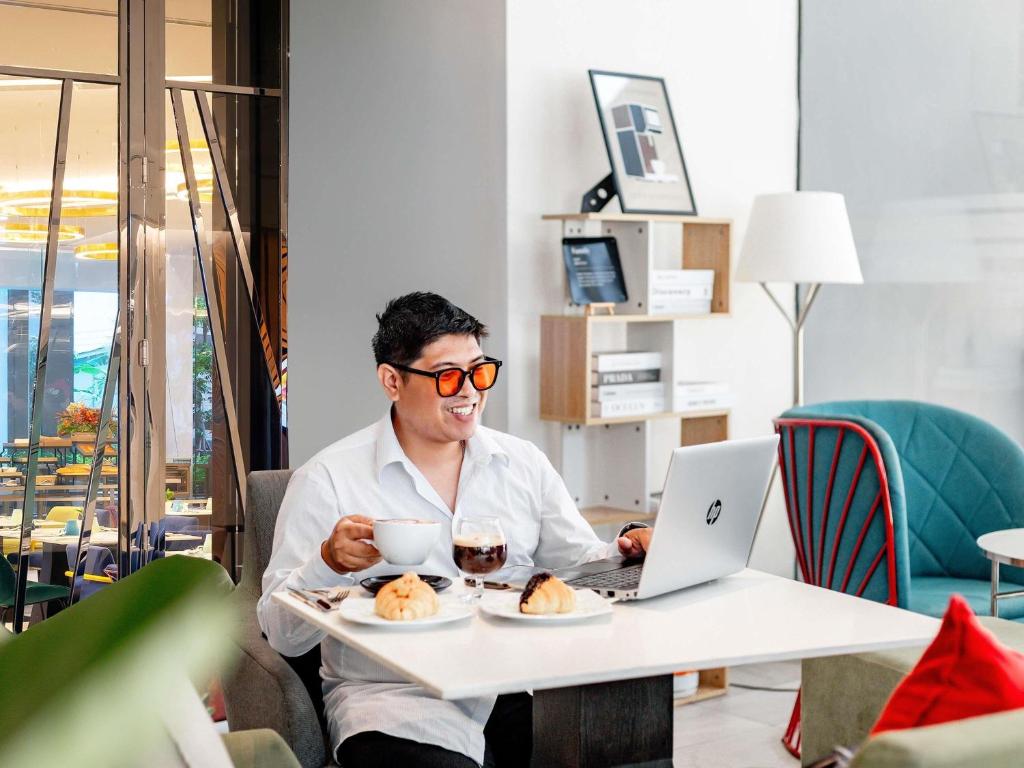 A guest using a laptop at a small table in a bright hotel lounge.