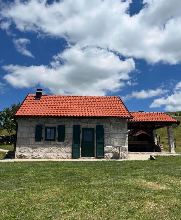 a small house with an orange roof on a field at Košara Trišnjevac in Lusnić