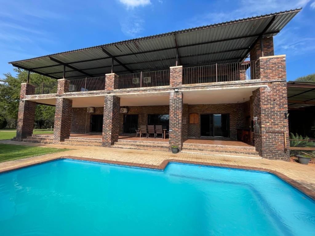a house with a swimming pool in front of a building at Emmanuel Guest Villa in Thabazimbi
