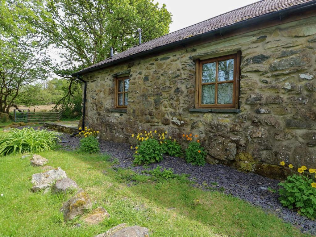 an old stone house with flowers in front of it at Bythyn Ddol Hafod in Capel Curig